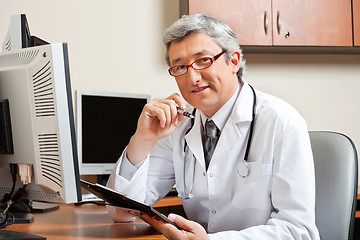 Image showing Doctor Sitting At Desk In Front Of Computer