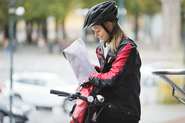 Image showing Female Cyclist Putting Package In Courier Bag