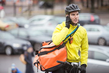 Image showing Male Cyclist With Courier Bag Using Mobile Phone On Street