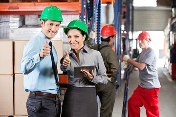 Image showing Supervisors Gesturing Thumbs Up At Warehouse