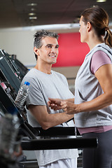 Image showing Instructor Looking At Female Client Exercising On Treadmill