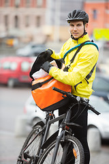 Image showing Male Cyclist Putting Package In Courier Bag On Street