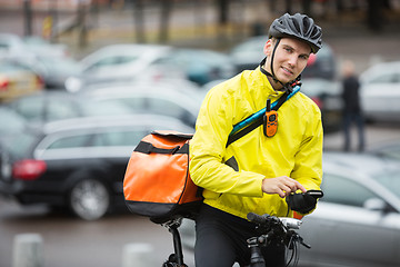 Image showing Male Cyclist With Courier Bag Using Mobile Phone On Street