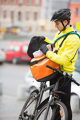 Image showing Young Male Cyclist Putting Package In Courier Bag