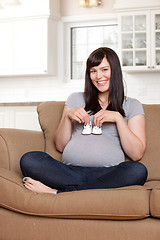 Image showing Happy Pregnant Woman Holding Baby Shoes