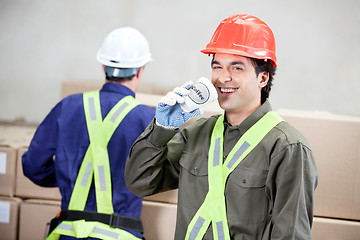 Image showing Foreman Drinking Coffee While Colleague Working At Warehouse