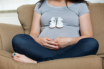 Image showing Pregnant Woman With Baby Shoes On Her Belly