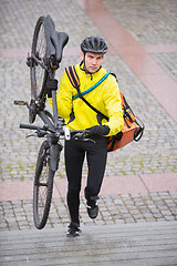 Image showing Male Cyclist With Bicycle And Courier Bag Walking Up Steps