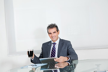 Image showing Businessman With Coffee Cup Using Digital Tablet In Office