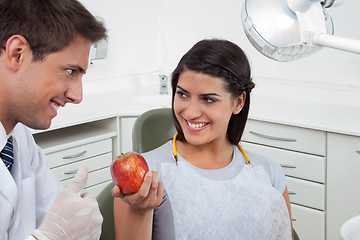 Image showing Dentist Showing Thumbs Up Sign To A Female Patient Holding An Ap