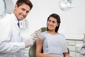 Image showing Happy Male Dentist Holding Thread While Patient Looking At Him