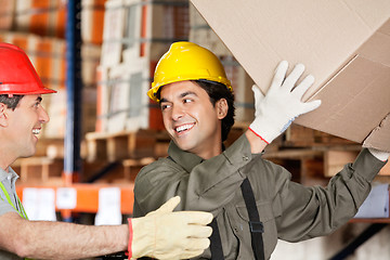 Image showing Foreman With Coworker Lifting Cardboard Box At Warehouse