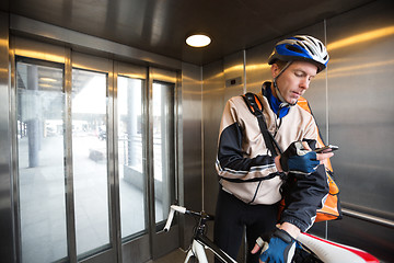 Image showing Male Cyclist With Courier Bag Using Mobile Phone In An Elevator