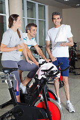 Image showing Man Holding Digital Tablet While Friends Exercising On Spinning