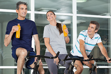 Image showing Man Looking At Friends With Juice Bottles On Spinning Bike