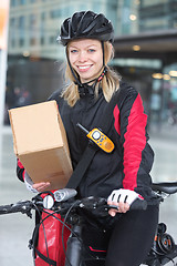 Image showing Female Cyclist With Cardboard Box And Courier Bag On Street