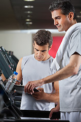 Image showing Instructor Making Notes While Standing Besides Man On Treadmill