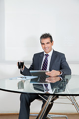 Image showing Businessman With Coffee Cup Using Digital Tablet In Office