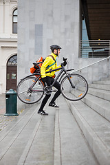 Image showing Courier Delivery Man With Bicycle And Backpack Walking Up Steps