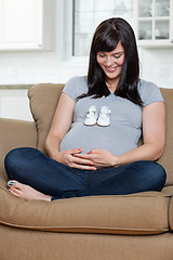 Image showing Pregnant Woman Looking At Baby Shoes On Her Belly