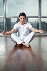 Image showing Young Man Meditating On Wooden Floor