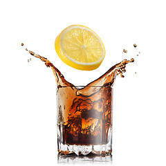 Image showing splash of cola in glass with lemon isolated on white