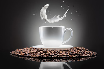 Image showing white cup with coffee beans and milk splash on black