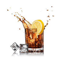 Image showing splash of cola in glass with lemon and ice isolated on white