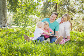 Image showing Young Family Enjoys Reading a Book in the Park