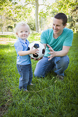 Image showing Young Boy and Dad Playing with Soccer Ball in Park