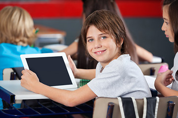 Image showing Cute Schoolboy Holding Digital Tablet In Classroom