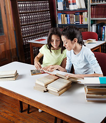 Image showing Schoolgirl Showing Book To Classmate In Library