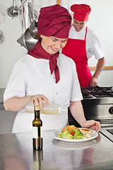 Image showing Female Chef Pouring Oil On Dish