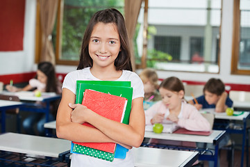 Image showing Schoolgirl Holding Books While Standing At Desk