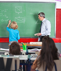 Image showing Rear View Of Little Boy Writing On Board In Classroom