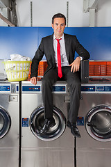 Image showing Businessman With Suitcase And Clothes Basket Sitting On Washing