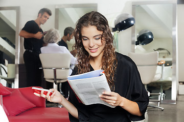 Image showing Woman With Mobile Phone Reading Magazine At Hair Salon