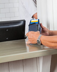 Image showing Man's Hands Making Payment Through Cellphone At Counter