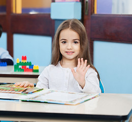 Image showing Girl With Popup Book Waving At Desk In Preschool