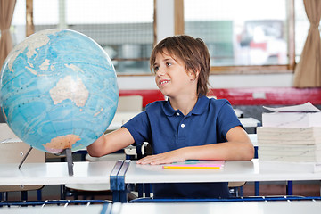 Image showing Schoolboy Searching Places On Globe At Desk