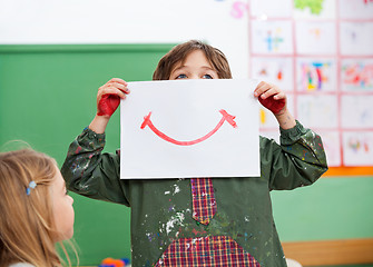 Image showing Boy Holding Drawing Paper On Face In Art Class