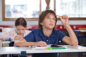 Image showing Boy Looking Up While Studying In Classroom