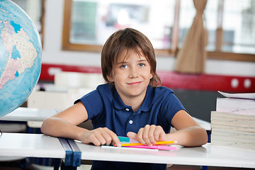 Image showing Little Boy Smiling While Sitting With Globe And Books At Desk