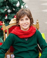 Image showing Boy Sitting On Chair Against Christmas Tree