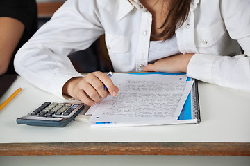 Image showing Schoolgirl With Calculator; Paper And Book At Desk