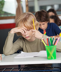 Image showing Bored Schoolboy Sitting At Desk In Classroom