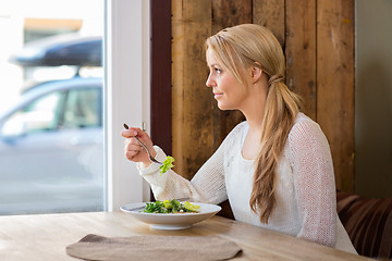 Image showing Woman Looking Through Window While Eating Salad