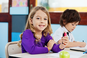 Image showing Girl Holding Color Pencils With Friend Drawing In Background