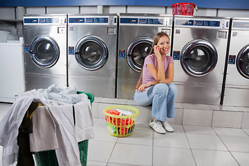 Image showing Beautiful Woman Using Mobile Phone At Laundry