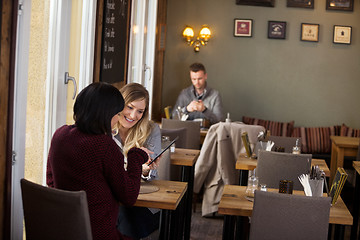 Image showing Female Friends Using Digital Tablet With Man In Background